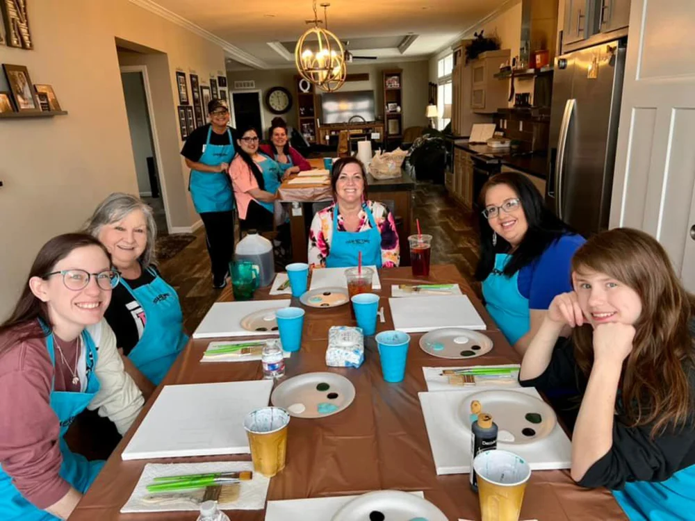 Guests seated along a long table at a private paint party at home
