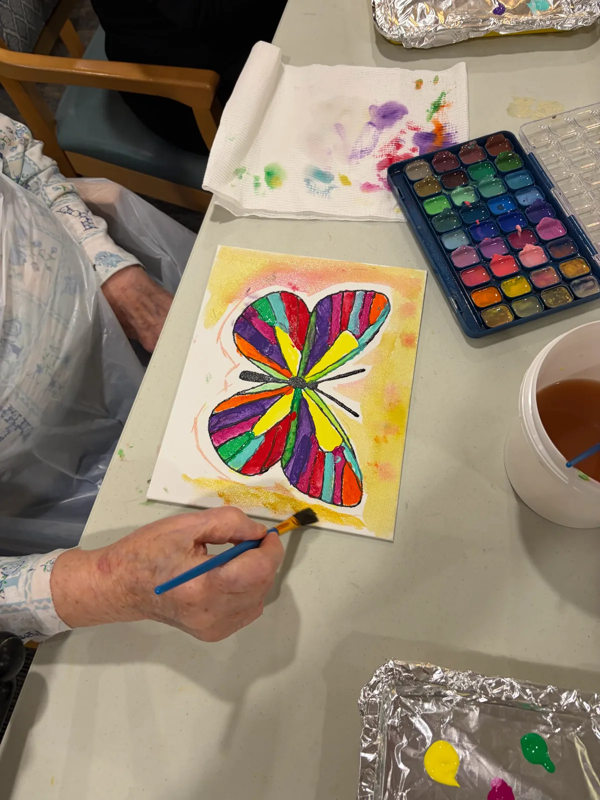 A resident carefully painting a butterfly artwork during a guided session